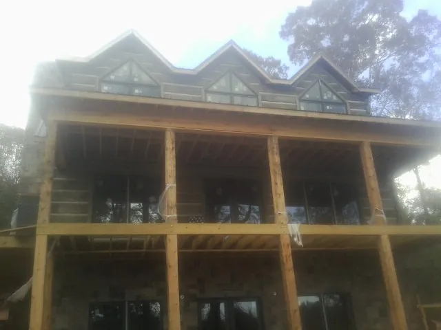 Dormers and porch framing on a large log home under construction — Roof Coating work by our crew in Vale